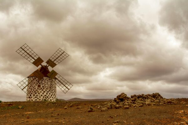 Old windmill in a desolate desert under cloudy skies, capturing a vintage feel in Spain.